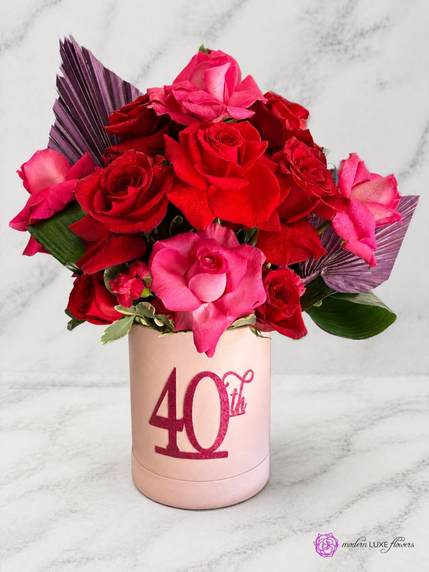 Red and hot pink roses with plum palm fans in a blush box marked 40th