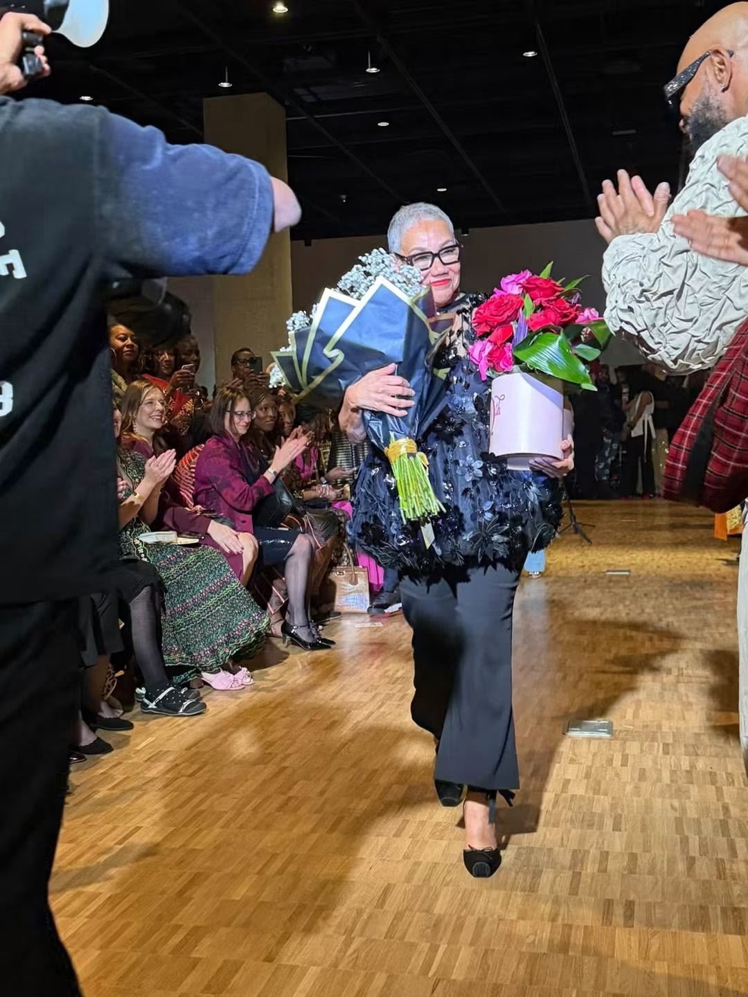 Barbara Bates on the runway holding a blush box of red and pink roses by Modern LUXE Flowers